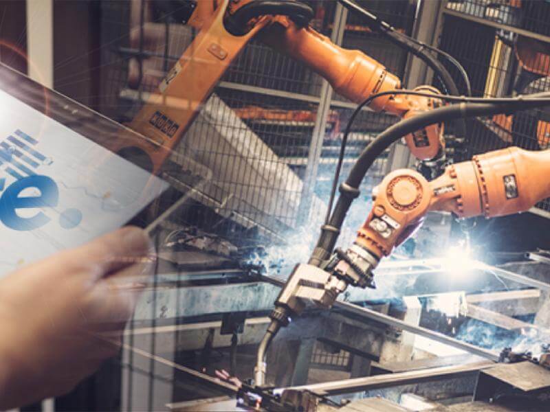 The text "Safe" on a display in front of industrial robots.