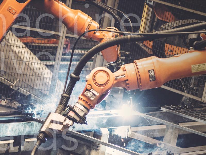 Industrial robots welding surrounded by mesh panels of Troax machine guarding.